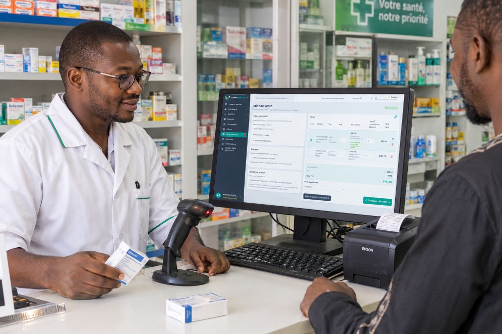 Pharmacien au comptoir utilisant Ahad Pharma : caisse, douchette et imprimante ticket